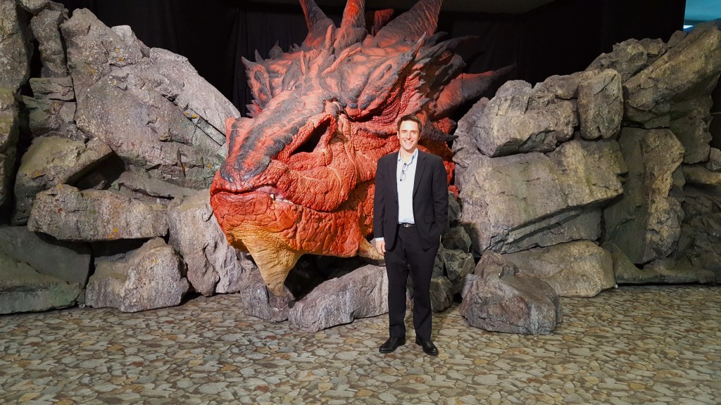Chad Fenner standing in front of a life-sized statue of Smaug the Dragon