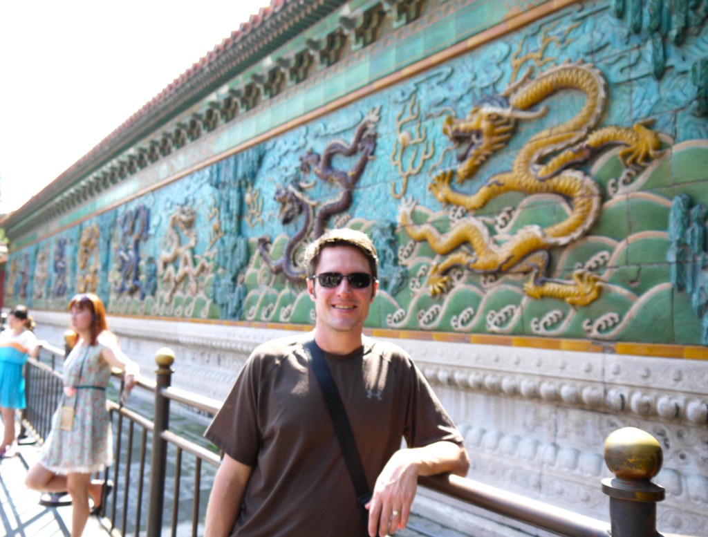 Chad Fenner posing in front of a large outdoor sculpture of dragons during an executive trip to Beijing
